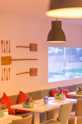 a dining room with a table and chairs and a window at Vila Gale Collection Praia in Albufeira