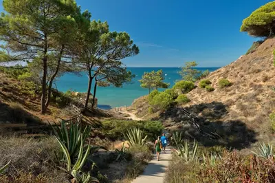 people walking down a trail with the ocean in the background at Alfagar Village in Albufeira