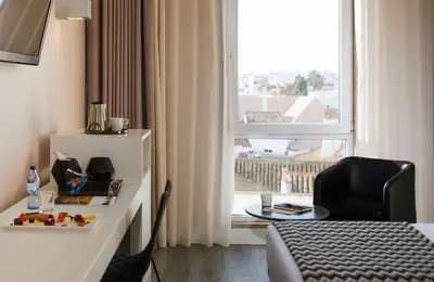 a hotel room with a bed and a chair and a window at Occidental Faro in Faro
