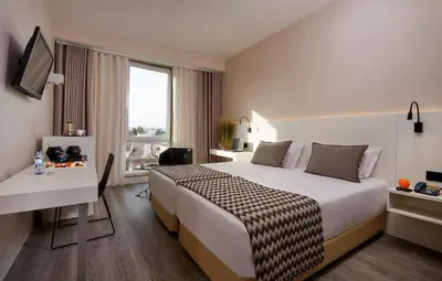a hotel room with a bed and a desk at Occidental Faro in Faro