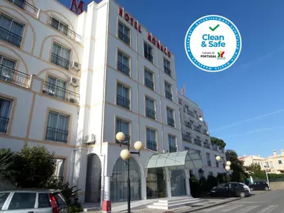 a large white building with a sign in front of it at Hotel Monaco in Faro