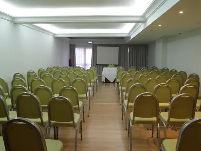 a room with a bunch of chairs and a white table at Hotel Monaco in Faro