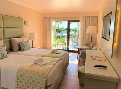 a hotel room with a bed and a desk and a balcony at Hotel Baia Grande in Albufeira
