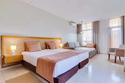 a hotel room with a large bed and a couch at Auramar Beach Resort in Albufeira