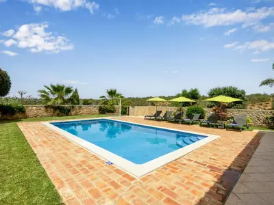 a swimming pool in a yard with chairs and umbrellas at Villa Villa Pescada by Interhome in Albufeira