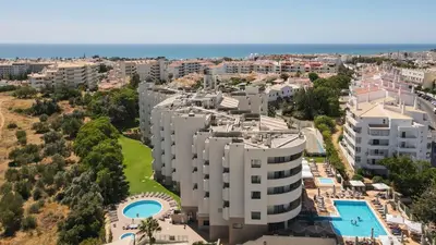 an apartment building with a car parked in front of it at Holiday Inn Algarve Albufeira by IHG in Albufeira