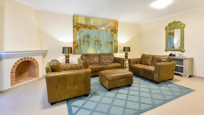 a living room with leather furniture and a fireplace at Martinhal Quinta Family Resort in Quinta do Lago