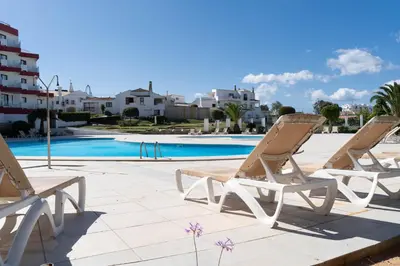 a couple of chairs sitting next to a swimming pool at Hotel da Aldeia - Adults Only in Albufeira