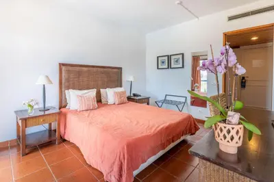 a bedroom with a bed and a vase of flowers at Hotel da Aldeia - Adults Only in Albufeira