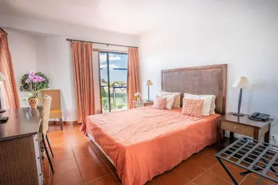 a bedroom with a bed and a desk and a window at Hotel da Aldeia - Adults Only in Albufeira
