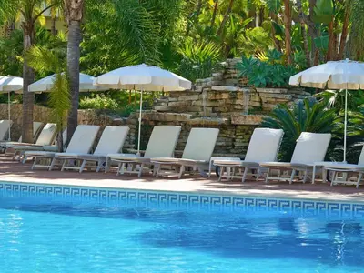 a group of lounge chairs and umbrellas next to a swimming pool at Ria Park Garden Hotel in Vale do Lobo