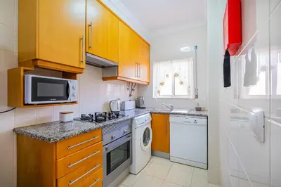 a kitchen with wooden cabinets and a washer and dryer at Pool&Beach in Encosta de São José in Albufeira