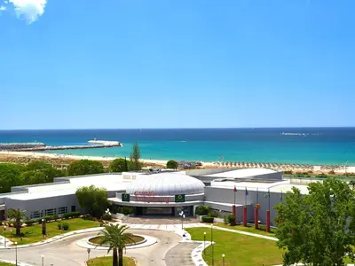a large building next to a beach with the ocean at Dom Pedro Portobelo in Vilamoura