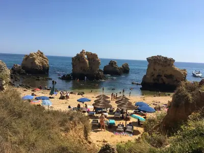 a group of people on a beach with umbrellas at Cosy and Sweet Apartment in Albufeira in Albufeira