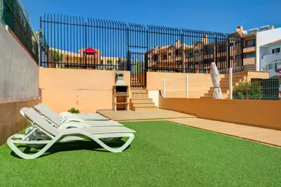a white lounge chair sitting on the grass on a building at Choromar Apartments in Albufeira
