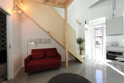 a red chair in a living room with a staircase at DUBOCAGE43 Citycenter in Faro