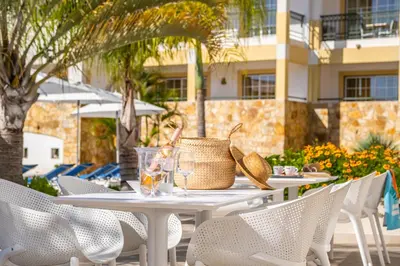 a white bedroom with two beds and a table at Apartamentos Turisticos Novochoro in Albufeira