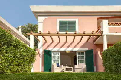 a pink house with chairs on the porch at Cegonha Country Club in Vilamoura