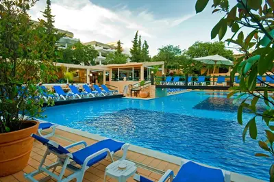 a swimming pool with blue chairs and a resort at Hotel Balaia Mar in Albufeira