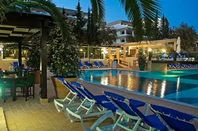 a swimming pool with blue chairs and a hotel at Hotel Balaia Mar in Albufeira