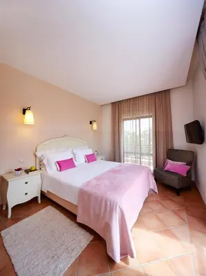 a bedroom with a large bed and a chair at Hotel Parque das Laranjeiras in Vilamoura