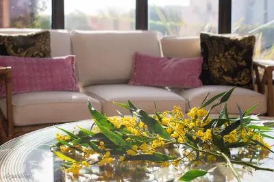 a living room with a couch and a table with yellow flowers at Hotel Parque das Laranjeiras in Vilamoura