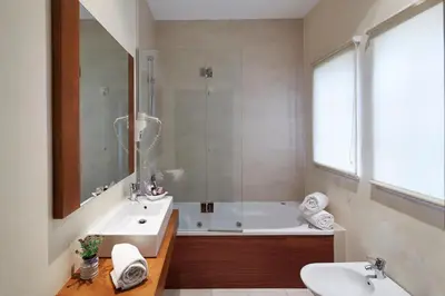 a bathroom with a tub and a sink and a mirror at Hotel Parque das Laranjeiras in Vilamoura