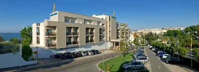 a large building with cars parked in a parking lot at Alisios in Albufeira