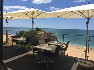 a patio with tables and umbrellas and a beach at Alisios in Albufeira