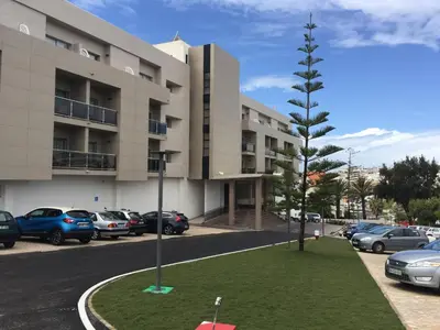 a parking lot with cars parked in front of a building at Alisios in Albufeira
