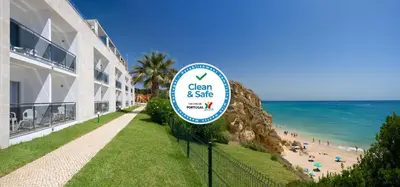 a sign in front of a hotel and a beach at Alisios in Albufeira