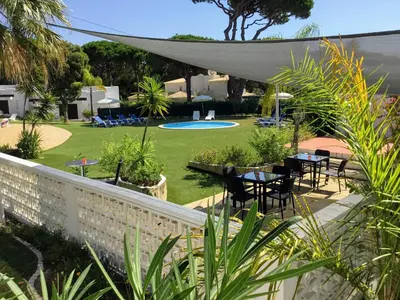 a garden with tables and chairs and a pool at Prado Villas in Vilamoura