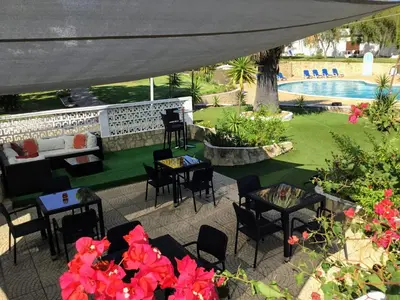an outdoor patio with tables and chairs and a pool at Prado Villas in Vilamoura