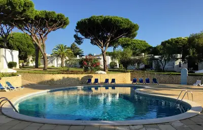 a swimming pool with chairs and trees at Prado Villas in Vilamoura
