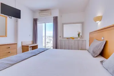 a white bedroom with a large bed and a window at Vila Recife Hotel in Albufeira