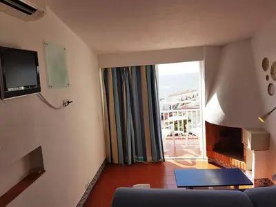 a living room with a couch and a sliding glass door at Apartamentos Turisticos Soldoiro in Albufeira