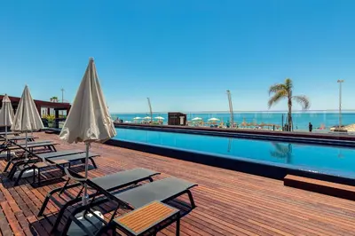 a row of chairs and umbrellas next to a swimming pool at Dom Jose Beach Hotel (Plus) in Quarteira