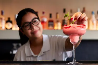 a woman holding a strawberry in a cocktail glass at Dom Jose Beach Hotel (Plus) in Quarteira