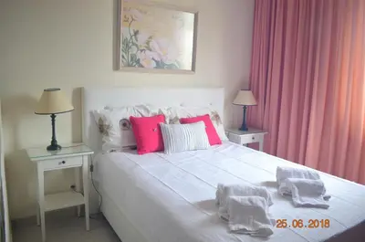 a bedroom with a white bed with pink pillows at Vilamoura-Nautic Apartment in Vilamoura