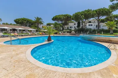 a large swimming pool in a resort with palm trees at Balaia Golf Village in Albufeira