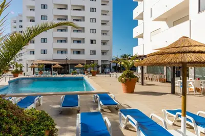 a swimming pool with lounge chairs and a hotel at Janelas do Mar Apartamentos Turisticos in Albufeira