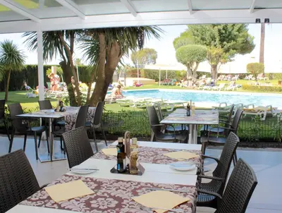 a restaurant with tables and chairs and a swimming pool at Parque Mourabel, Oásis Village & Pé do Lago in Vilamoura