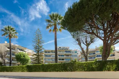 a large building with palm trees in front of it at Parque Mourabel, Oásis Village & Pé do Lago in Vilamoura