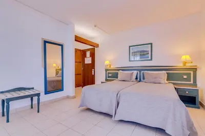 a bedroom with a bed and a table and a mirror at Hotel Mar A Vista in Albufeira