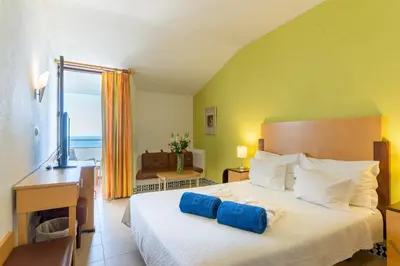 a bedroom with a bed with blue pillows on it at Boa Vista Hotel & Spa - Adults Only in Albufeira