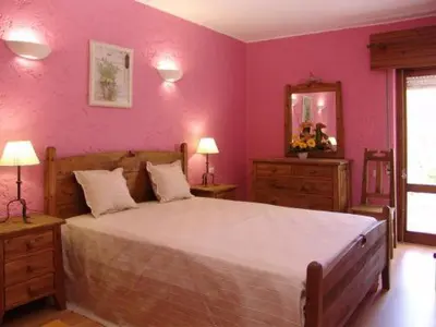 a bedroom with a large bed with pink walls at Oleandro Country Club in Albufeira