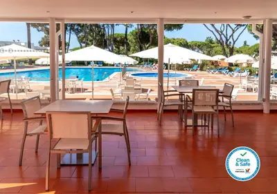 a restaurant with tables and chairs and a swimming pool at Apartamentos Turisticos Pinhal Da Marina in Vilamoura