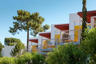 a building with yellow doors and a tree at Apartamentos Turisticos Pinhal Da Marina in Vilamoura