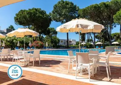 a group of chairs and umbrellas next to a pool at Apartamentos Turisticos Pinhal Da Marina in Vilamoura
