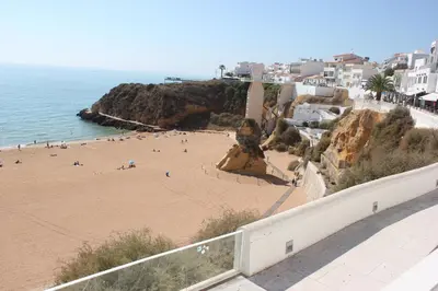 a beach with people on the sand and buildings at Rocamar Exclusive Hotel & Spa - Adults Only in Albufeira